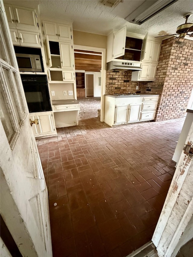 kitchen featuring brick floor, under cabinet range hood, a ceiling fan, black oven, and stainless steel microwave