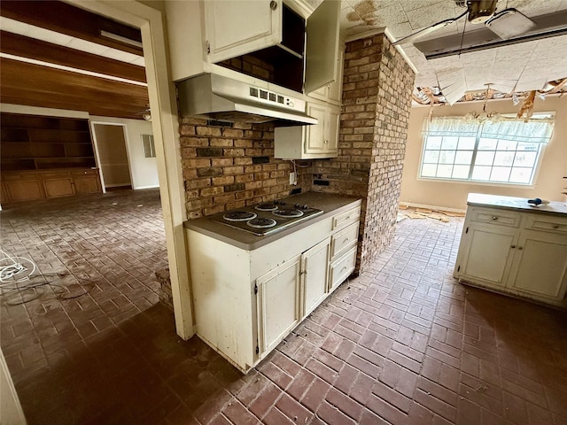 kitchen with brick floor, stainless steel electric cooktop, range hood, beam ceiling, and decorative backsplash