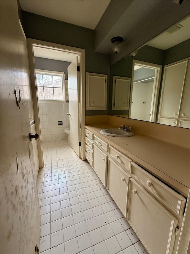 bathroom featuring tile patterned flooring, vanity, toilet, and tile walls