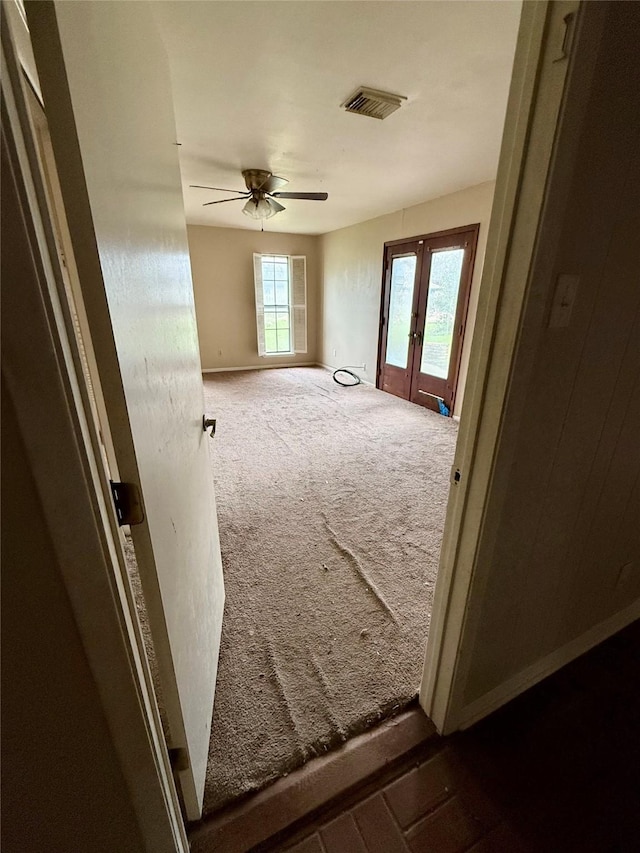 spare room featuring a wealth of natural light, french doors, visible vents, and dark carpet