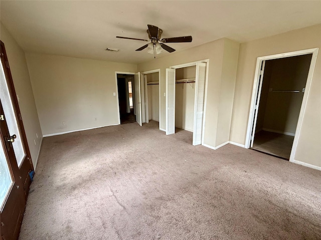 unfurnished bedroom with baseboards, carpet, visible vents, and multiple closets