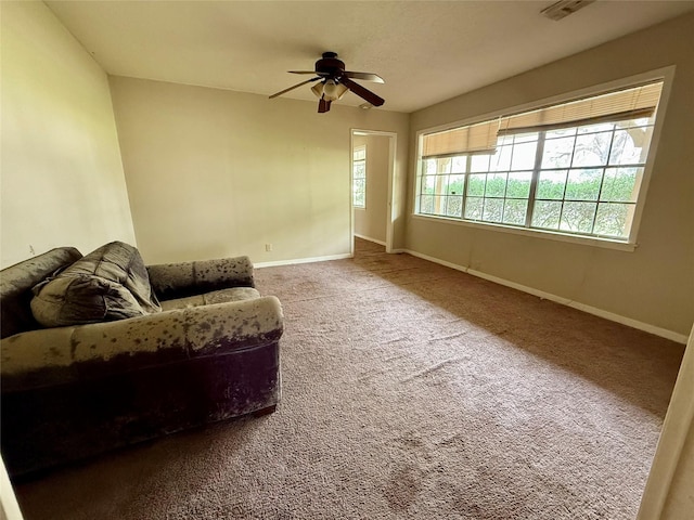 carpeted living room with visible vents, baseboards, and a ceiling fan