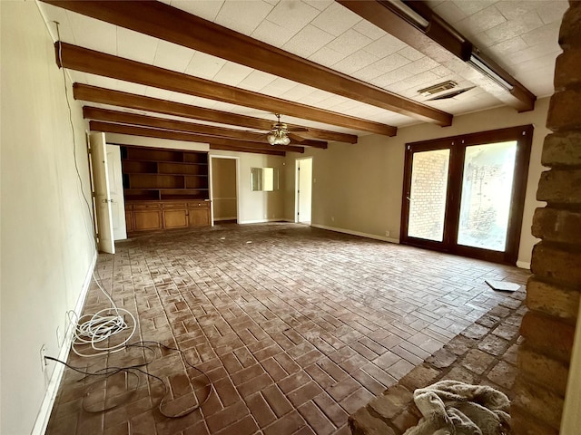 unfurnished living room with brick floor, beam ceiling, visible vents, ceiling fan, and baseboards