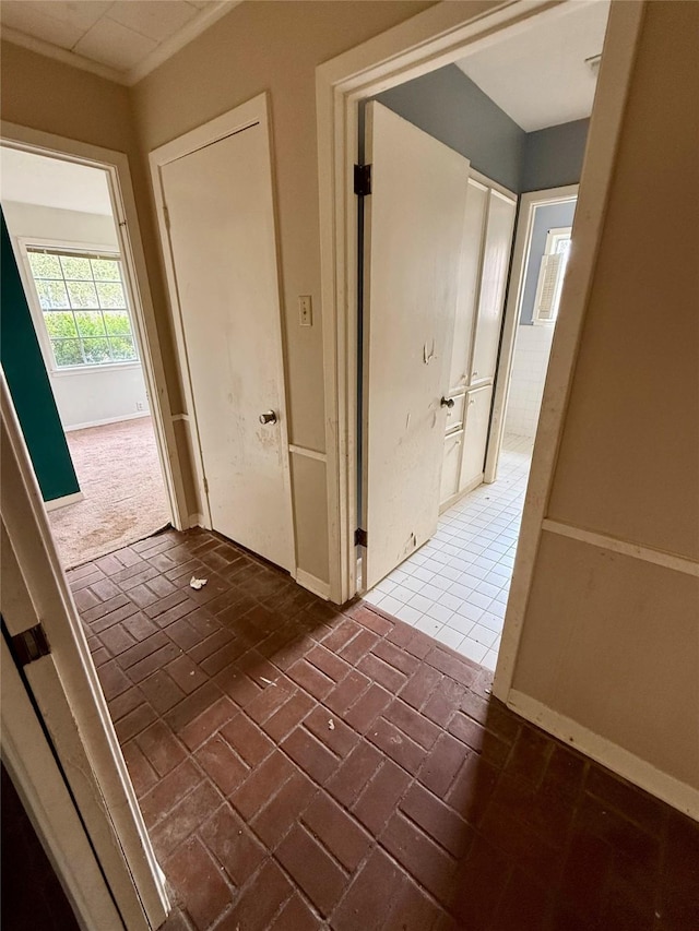 corridor featuring brick floor and baseboards