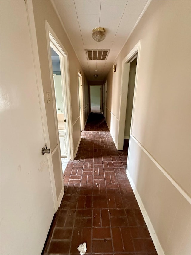 corridor featuring brick floor, visible vents, and baseboards