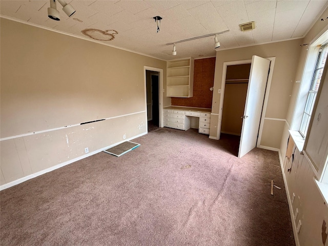 unfurnished bedroom featuring carpet floors, built in study area, crown molding, and visible vents