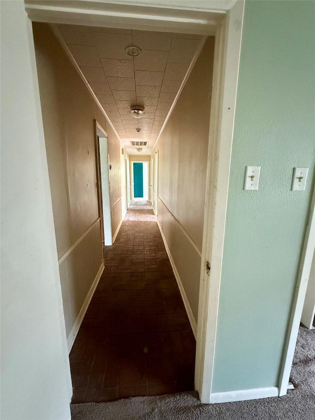 hall with ornamental molding and a paneled ceiling