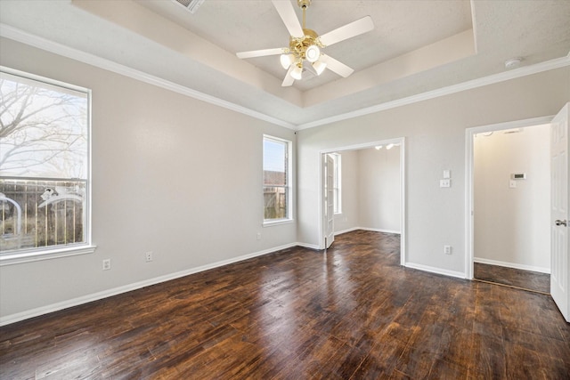 empty room with dark hardwood / wood-style flooring, ornamental molding, a raised ceiling, and ceiling fan