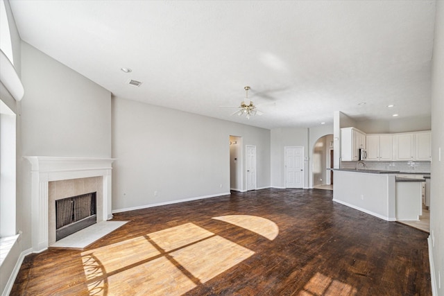 unfurnished living room featuring dark hardwood / wood-style floors, ceiling fan, and a fireplace