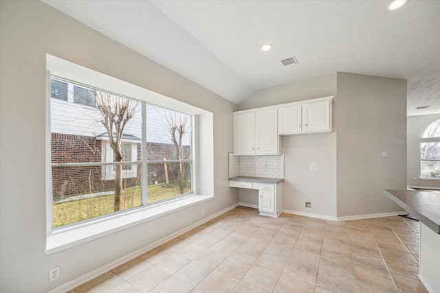 kitchen featuring a wealth of natural light, built in desk, and white cabinets