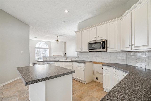 kitchen with white cabinetry, a center island, sink, and decorative backsplash