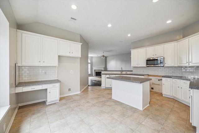 kitchen with ceiling fan, a kitchen island, and white cabinets