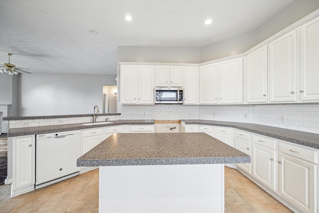 kitchen with sink, white cabinetry, white dishwasher, a kitchen island, and backsplash