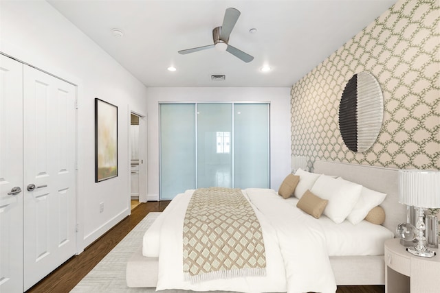 bedroom featuring dark hardwood / wood-style flooring, two closets, and ceiling fan