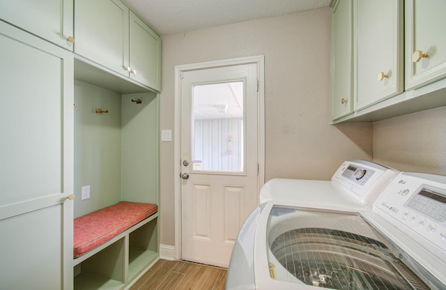 clothes washing area with cabinets, washer and clothes dryer, and light hardwood / wood-style floors