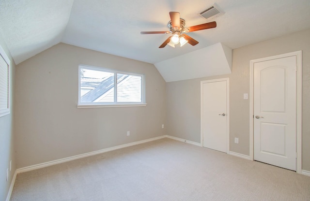 additional living space featuring ceiling fan, lofted ceiling, light colored carpet, and a textured ceiling