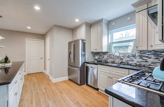 kitchen featuring appliances with stainless steel finishes, tasteful backsplash, sink, white cabinets, and light wood-type flooring