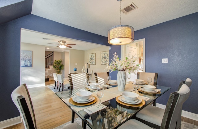 dining area with ceiling fan, lofted ceiling, hardwood / wood-style floors, and a textured ceiling