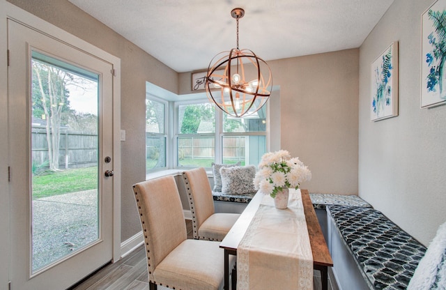 dining room featuring wood-type flooring, a healthy amount of sunlight, and a notable chandelier