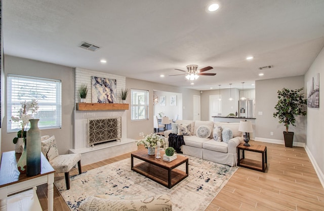 living room with a premium fireplace, ceiling fan, and light hardwood / wood-style flooring