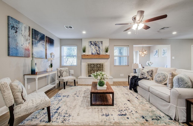 living room with hardwood / wood-style flooring, ceiling fan, and a fireplace