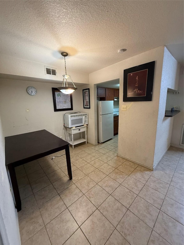 unfurnished dining area with a textured ceiling and light tile patterned floors