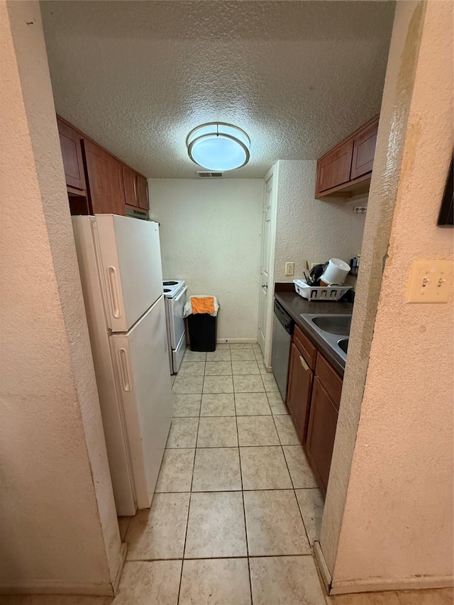 kitchen with sink, light tile patterned floors, a textured ceiling, and white appliances