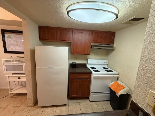 kitchen with light tile patterned flooring, white appliances, and a textured ceiling