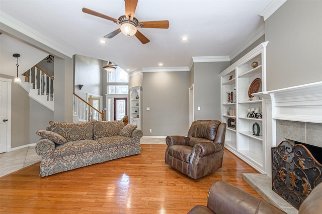 living room with ornamental molding, built in features, a fireplace, and light wood-type flooring