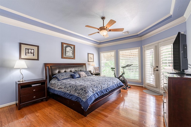 bedroom featuring crown molding, a tray ceiling, access to exterior, and light hardwood / wood-style floors