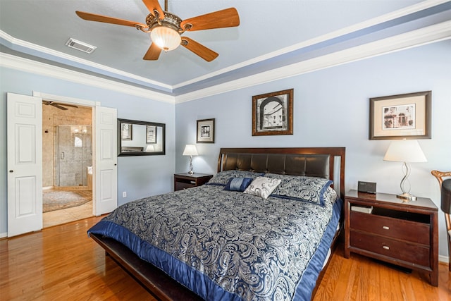 bedroom with crown molding, ceiling fan, hardwood / wood-style floors, connected bathroom, and a tray ceiling