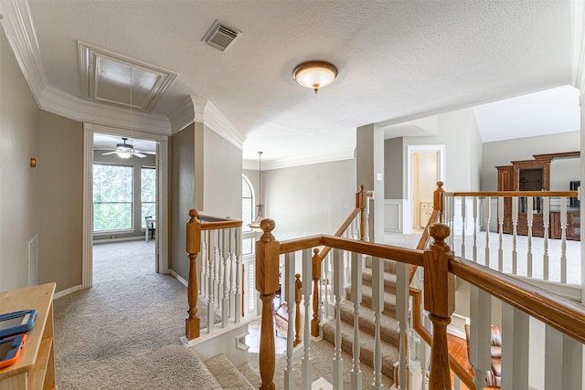 hallway featuring ornamental molding, light carpet, and a textured ceiling