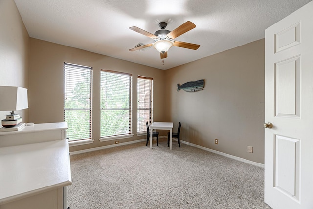 unfurnished office featuring ceiling fan, light colored carpet, and a textured ceiling