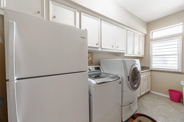 laundry room featuring light tile patterned floors, washer and clothes dryer, and cabinets