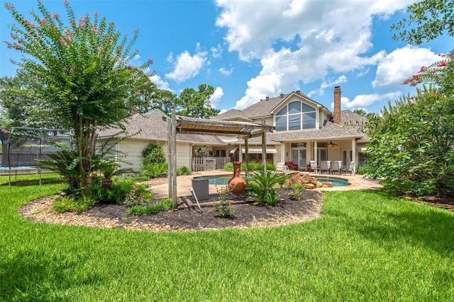 back of house featuring a trampoline, a fenced in pool, a patio area, and a lawn