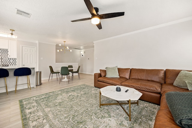 living room featuring a textured ceiling, light hardwood / wood-style flooring, ornamental molding, and ceiling fan