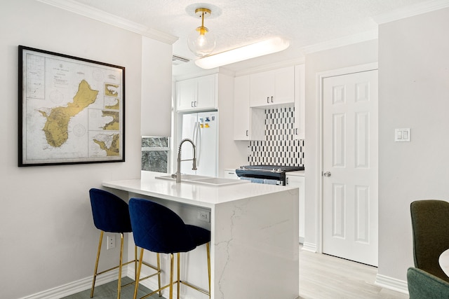 kitchen featuring a breakfast bar area, white cabinetry, white refrigerator, kitchen peninsula, and pendant lighting