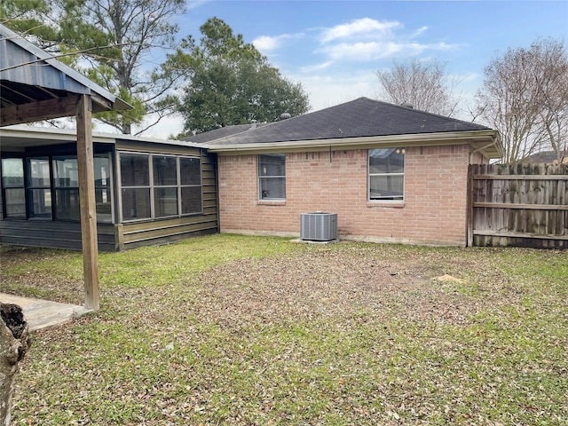 rear view of property with a lawn, a sunroom, and central air condition unit