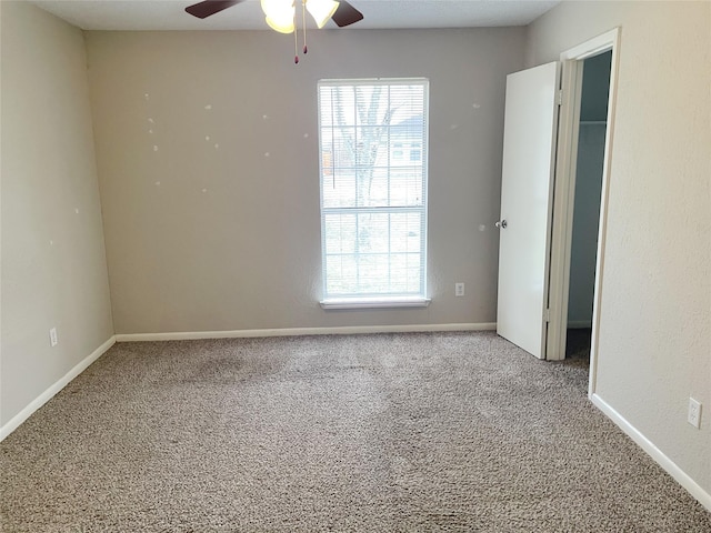 empty room with carpet flooring, a wealth of natural light, and ceiling fan