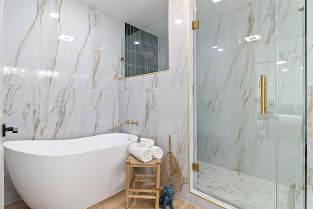 bathroom featuring hardwood / wood-style flooring, plus walk in shower, and tile walls