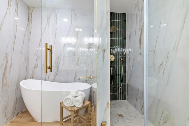 bathroom featuring hardwood / wood-style floors, plus walk in shower, and tile walls