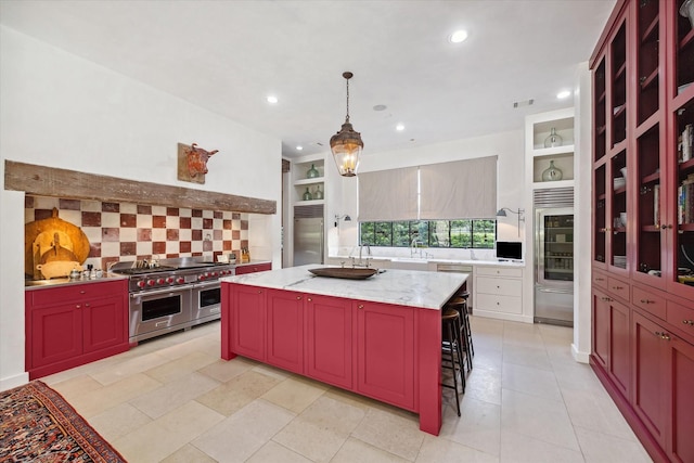 kitchen featuring a breakfast bar area, premium appliances, light stone countertops, a kitchen island, and decorative light fixtures