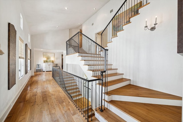 staircase with a towering ceiling and wood-type flooring