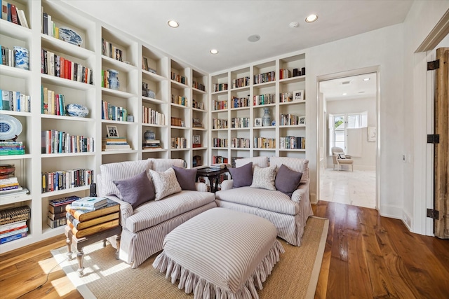 sitting room with wood-type flooring and built in shelves