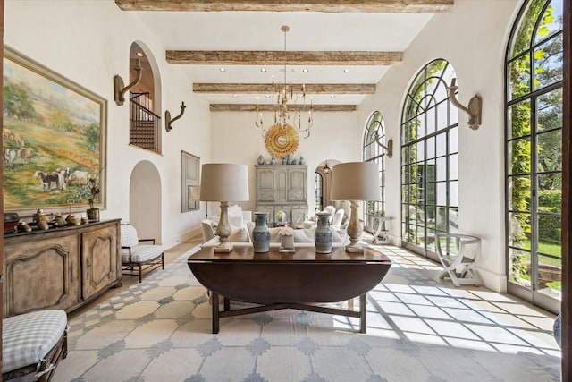 interior space with beamed ceiling, plenty of natural light, a towering ceiling, and a notable chandelier