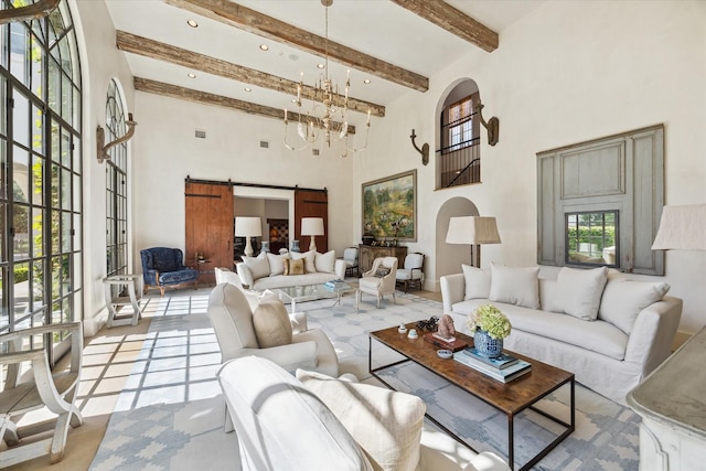 living room featuring a high ceiling, a barn door, a notable chandelier, and beamed ceiling