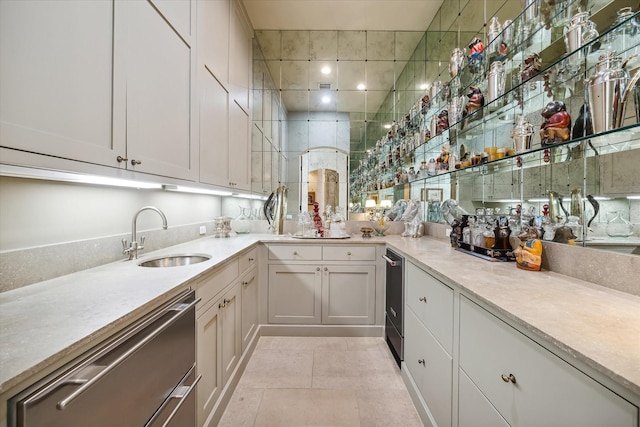 kitchen featuring white cabinetry, sink, stainless steel dishwasher, and light tile patterned floors