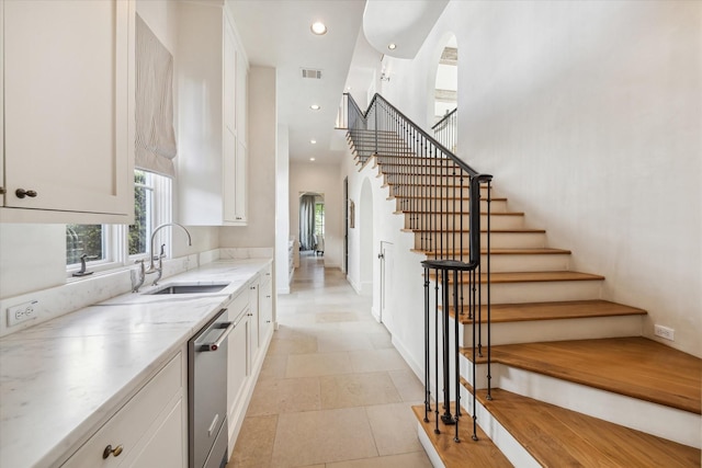 kitchen with a high ceiling, dishwasher, sink, and white cabinets