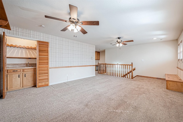 empty room with wet bar, light colored carpet, and a textured ceiling