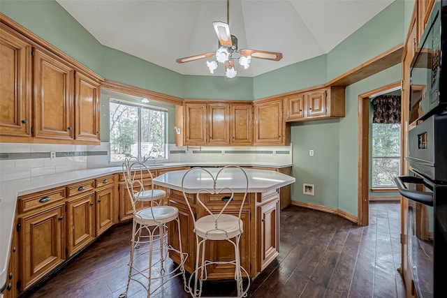 kitchen featuring tasteful backsplash, a kitchen island, dark hardwood / wood-style floors, and a kitchen breakfast bar